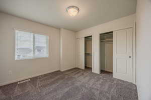 Unfurnished bedroom featuring multiple closets, carpet, and a textured ceiling