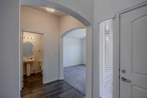 Hallway featuring arched walkways and dark wood-style floors