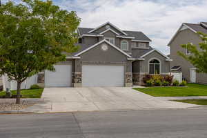 View of front of house featuring stone siding, roof with shingles, and concrete driveway