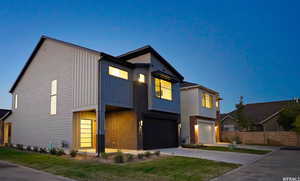 Contemporary home with board and batten siding, an attached garage, driveway, and brick siding