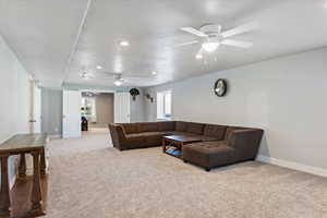 Carpeted living room featuring a textured ceiling, recessed lighting, and ceiling fan