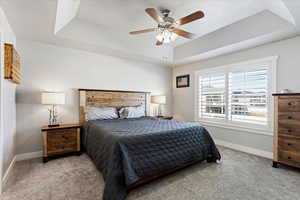 Bedroom with a tray ceiling, carpet, and a ceiling fan