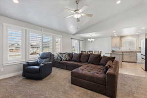Living room with vaulted ceiling, recessed lighting, ceiling fan, a chandelier, and light colored carpet