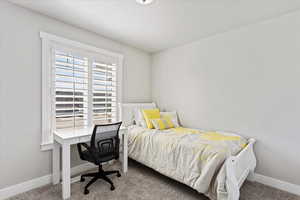 Carpeted bedroom featuring baseboards and an office area