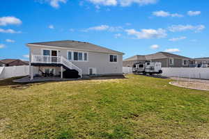 Back of property with a fenced backyard, a wooden deck, and stucco siding