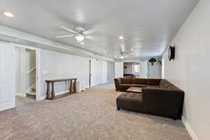 Carpeted living room with recessed lighting, stairway, and a ceiling fan