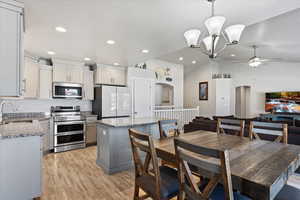 Kitchen featuring appliances with stainless steel finishes, arched walkways, vaulted ceiling, light wood-style flooring, and open floor plan