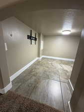 Basement with baseboards and a textured ceiling