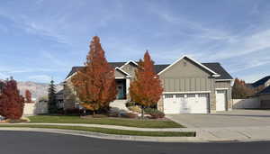 View of front of home featuring board and batten siding, concrete driveway, stone siding, and an attached garage
