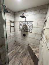 Full bath with tiled shower and wood finished floors