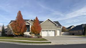 Craftsman-style house with board and batten siding, driveway, stone siding, and an attached garage
