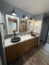 Full bathroom featuring double vanity and dark wood-style flooring