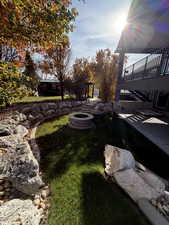 View of grassy yard featuring a fire pit, stairway, and a patio