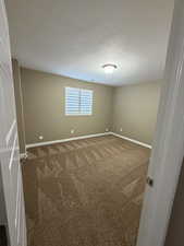Unfurnished room with carpet and a textured ceiling