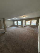 Spare room with dark carpet and a textured ceiling