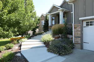 Property entrance featuring stone siding, a garage, and board and batten siding