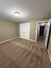 Unfurnished bedroom featuring carpet, a textured ceiling, and a closet