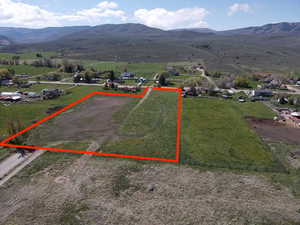 Aerial view of sparsely populated area featuring property parcel outlined and a mountainous background