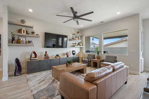 Living room with light wood-style floors, a ceiling fan, and recessed lighting