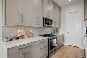 Kitchen with gray cabinetry, stainless steel appliances, tasteful backsplash, and recessed lighting