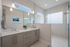 Bathroom featuring a walk in shower, double vanity, tile patterned floors, and recessed lighting