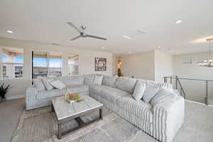 Living area featuring carpet floors, ceiling fan, recessed lighting, and a chandelier