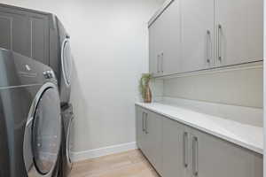 Laundry area with cabinet space, washer and clothes dryer, and light wood-type flooring
