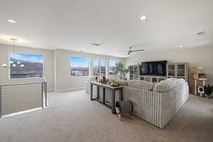Living area with light colored carpet, recessed lighting, ceiling fan, a mountain view, and a chandelier