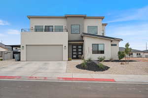 Modern home featuring a garage, stucco siding, driveway, and a balcony