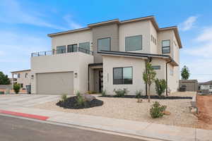 Contemporary home with a balcony, concrete driveway, and stucco siding