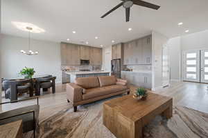 Living room featuring light wood-style floors, recessed lighting, a chandelier, and a ceiling fan