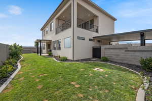 Rear view of house with a balcony, a fenced backyard, and stucco siding