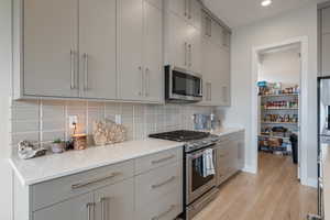 Kitchen featuring gray cabinetry, appliances with stainless steel finishes, decorative backsplash, and recessed lighting