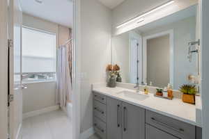 Full bath with vanity, shower / bath combo, and tile patterned flooring