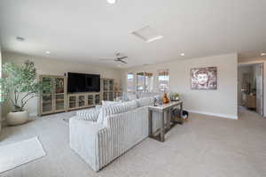 Living area featuring light colored carpet, ceiling fan, and recessed lighting