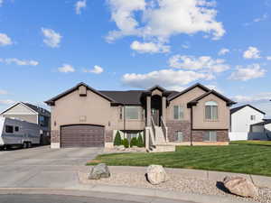 View of front of home featuring stucco siding, driveway, a front lawn, brick siding, and a residential view