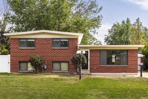 Split level home featuring a front yard and brick siding