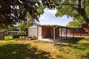 Rear view of property featuring a patio area, concrete block siding, and a garden