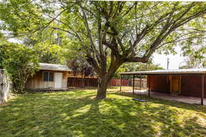 Fenced backyard with an outdoor structure and a patio