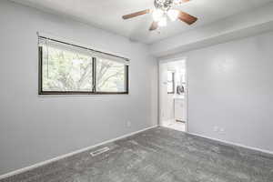 Unfurnished bedroom featuring carpet, ensuite bathroom, and ceiling fan