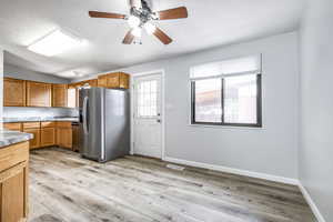 Kitchen with stainless steel fridge with ice dispenser, a ceiling fan, light wood-style floors, a textured ceiling, and vaulted ceiling