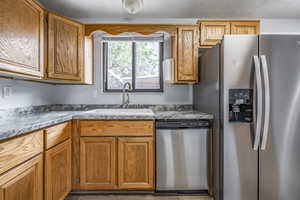 Kitchen with appliances with stainless steel finishes, brown cabinets, a textured ceiling, and light countertops