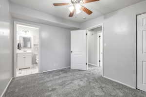 Unfurnished bedroom with carpet flooring, ensuite bathroom, and a ceiling fan