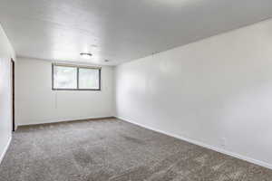 Carpeted spare room featuring baseboards and a textured ceiling