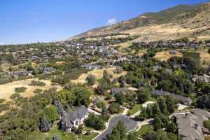 Aerial view of property and surrounding area featuring nearby suburban area and a mountain backdrop