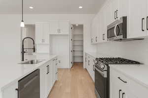 Kitchen with appliances with stainless steel finishes, recessed lighting, white cabinetry, light wood-style floors, and light countertops