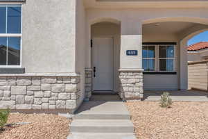 Doorway to property featuring stucco siding and stone siding
