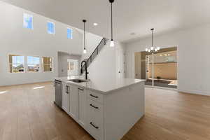 Kitchen with light wood-style floors, open floor plan, white cabinetry, light countertops, and healthy amount of natural light