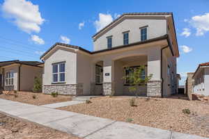 Mediterranean / spanish house featuring stone siding, covered porch, and stucco siding