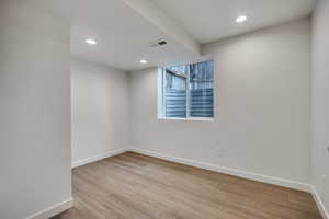 Unfurnished room featuring wood finished floors, recessed lighting, and a textured wall